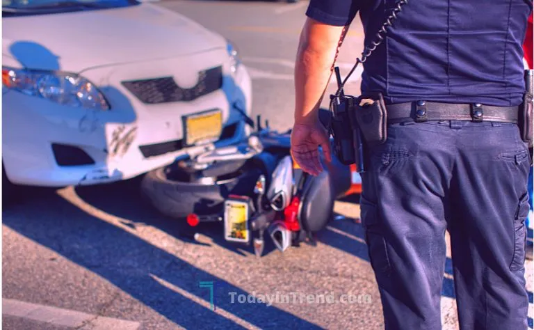 Police officer standing near a car and a fallen motorcycle after a crash